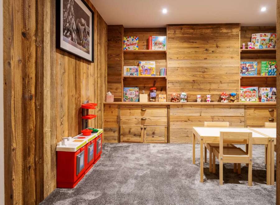 This charming children's playroom features a rustic wooden wall and a cozy grey carpet, creating a warm and inviting atmosphere.