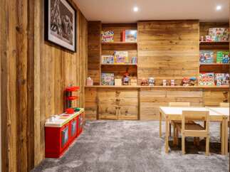 This charming children's playroom features a rustic wooden wall and a cozy grey carpet, creating a warm and inviting atmosphere.