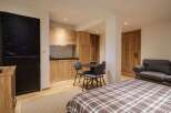 This charming studio apartment features a modern kitchenette with light wood cabinetry, perfect for preparing meals.