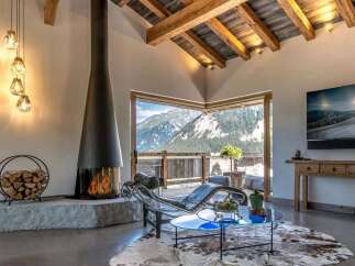 Experience breathtaking mountain views from this luxurious living room, featuring a modern fireplace and a sleek chaise lounge.