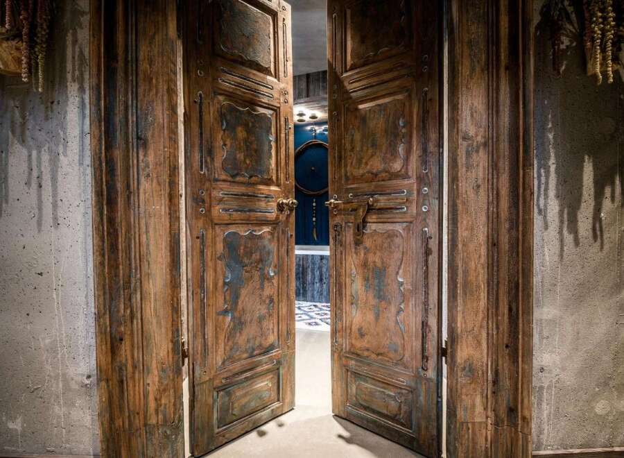 Step through these magnificent, antique wooden double doors, showcasing intricate carvings and a distressed finish that adds character and history.