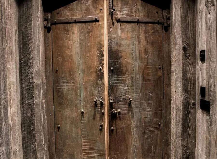 Step into a world of rustic charm with these magnificent double doors, crafted from weathered wood and adorned with heavy-duty iron hardware.