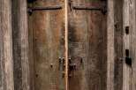 Step into a world of rustic charm with these magnificent double doors, crafted from weathered wood and adorned with heavy-duty iron hardware.