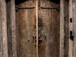 Step into a world of rustic charm with these magnificent double doors, crafted from weathered wood and adorned with heavy-duty iron hardware.