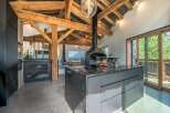 Experience luxury mountain living in this stunning open-plan kitchen and dining area, featuring exposed wooden beams and a modern fireplace.