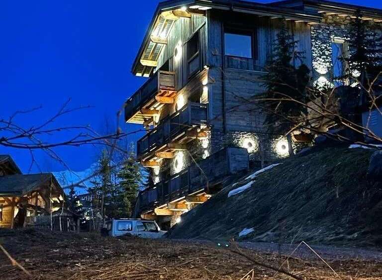 Experience luxury mountain living in this stunning chalet, featuring a rustic wooden exterior complemented by stone accents.
