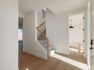 Step into this bright and airy entryway, featuring a modern staircase with sleek black spindles and a warm wooden handrail.