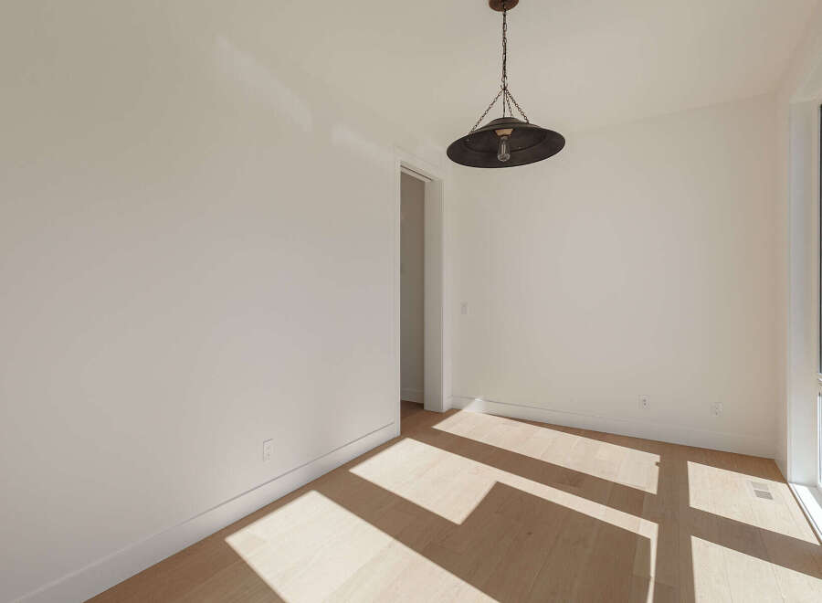 Bathed in natural light, this empty room features a striking industrial pendant light hanging from the ceiling.
