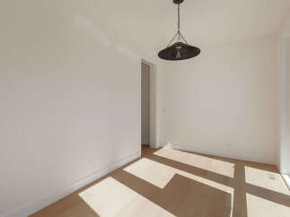 Bathed in natural light, this empty room features a striking industrial pendant light hanging from the ceiling.