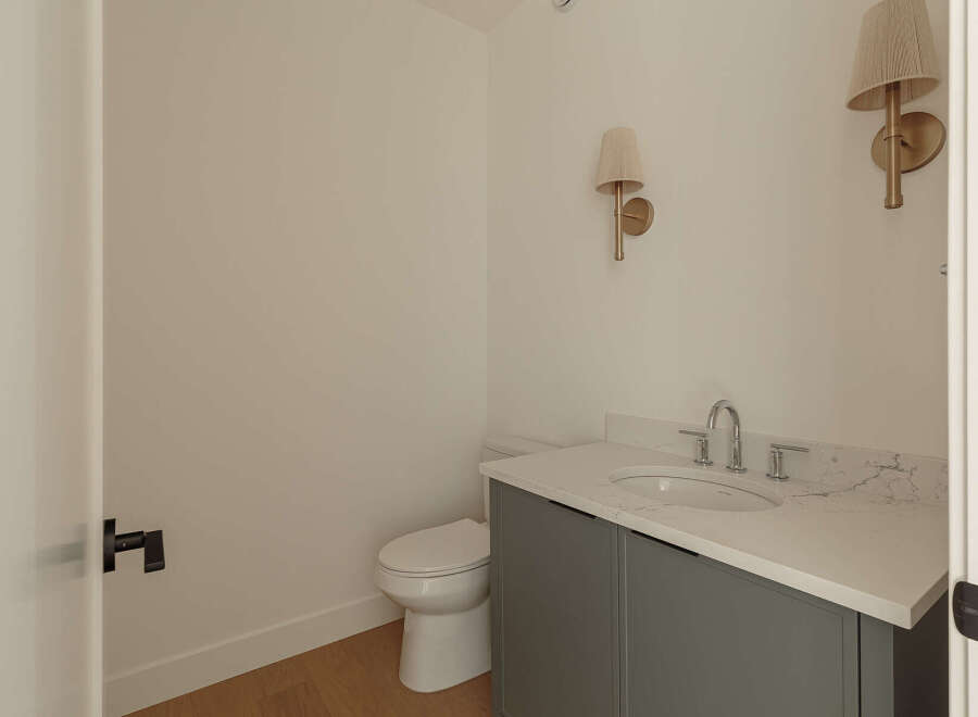 This modern bathroom features a sleek gray vanity with a white quartz countertop and an undermount sink.
