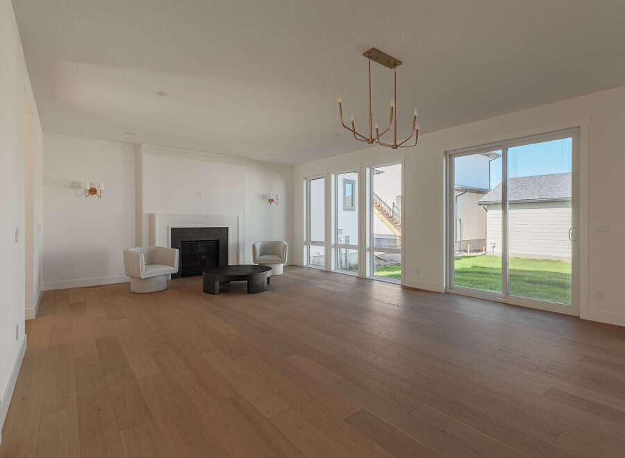 Experience modern living in this spacious great room, featuring a sleek fireplace and ample natural light from large windows.