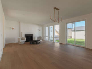Experience modern living in this spacious great room, featuring a sleek fireplace and ample natural light from large windows.