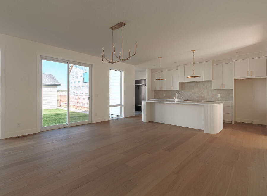 Experience modern living in this spacious open-concept home, featuring a sleek white kitchen with ample cabinet space and a large island perfect for entertaining.