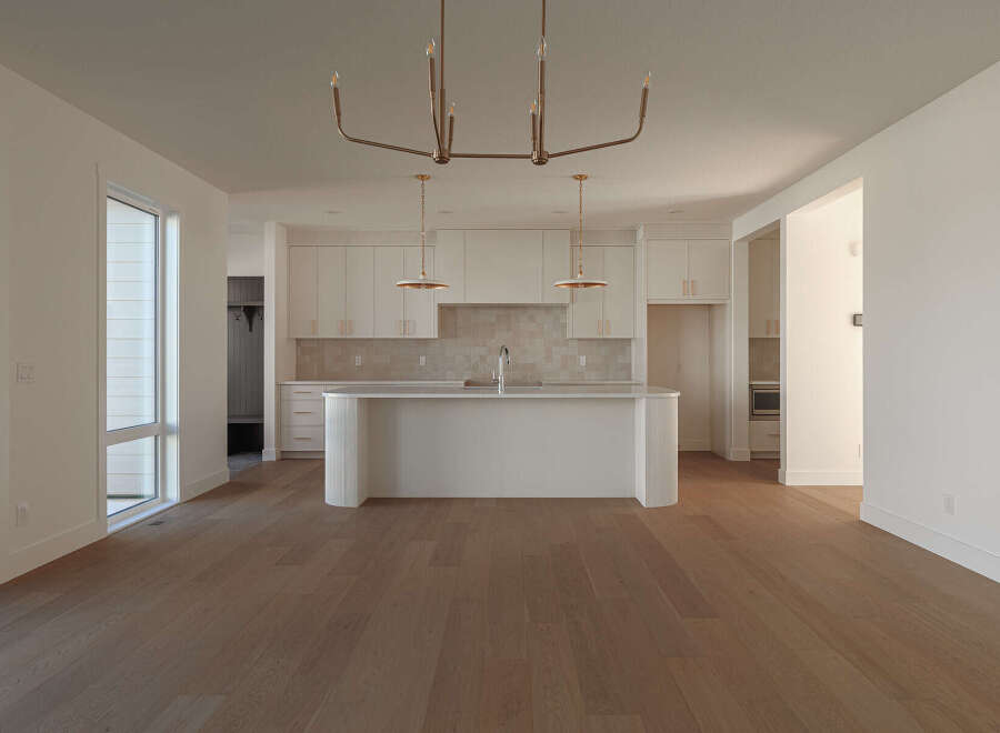Experience modern living in this spacious open-concept home, featuring a sleek white kitchen with a large island and ample cabinet space.
