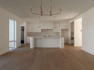 Experience modern living in this spacious open-concept home, featuring a sleek white kitchen with a large island and ample cabinet space.