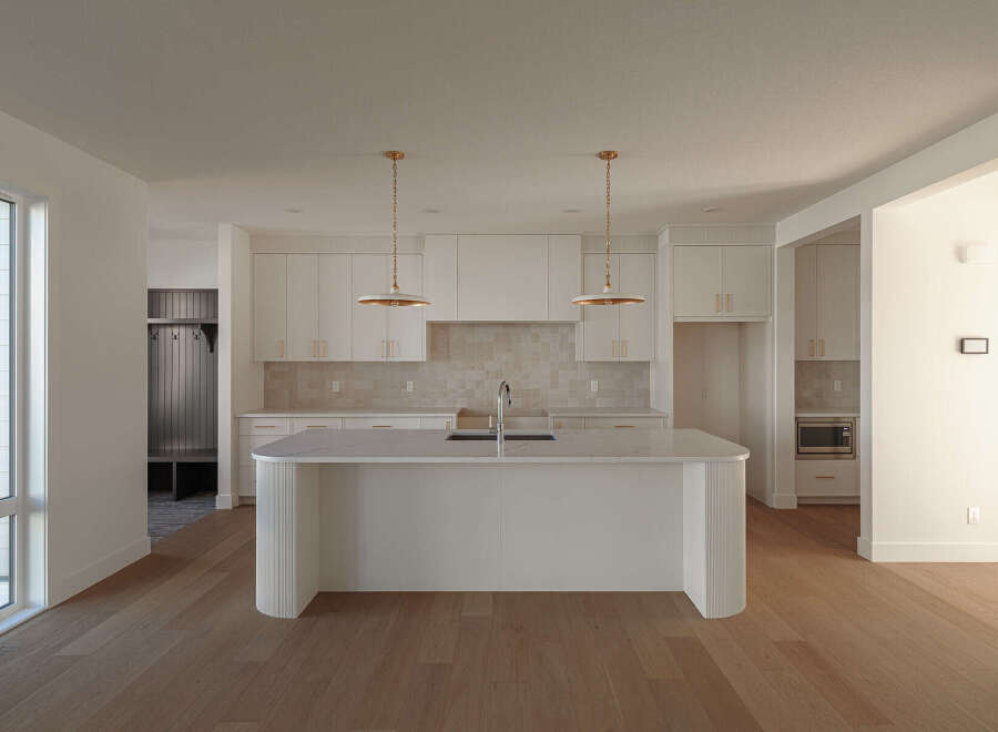 Experience modern living in this stunning kitchen featuring a large island with a waterfall countertop, perfect for entertaining.
