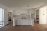 Experience modern living in this stunning kitchen featuring a large island with a waterfall countertop, perfect for entertaining.
