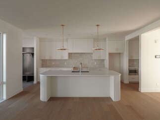 Experience modern living in this stunning kitchen featuring a large island with a waterfall countertop, perfect for entertaining.