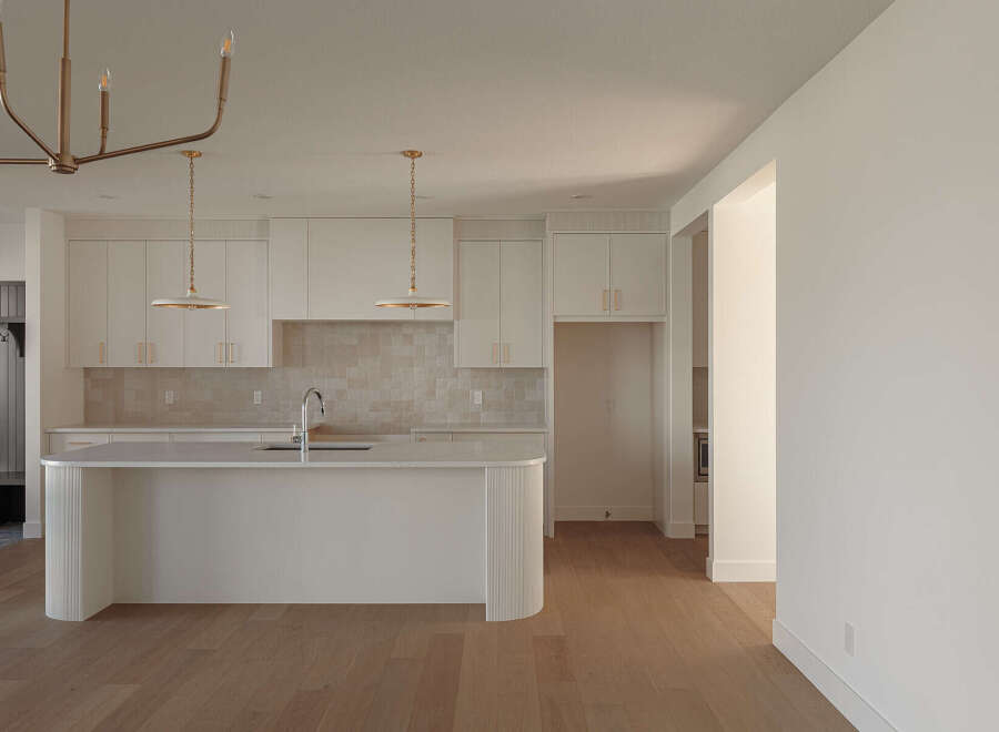 Experience modern living in this stunning kitchen featuring sleek white cabinetry and a spacious island perfect for entertaining.