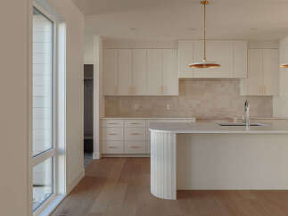 Experience modern luxury in this stunning kitchen, featuring sleek white cabinetry with elegant gold hardware and a chic tiled backsplash.