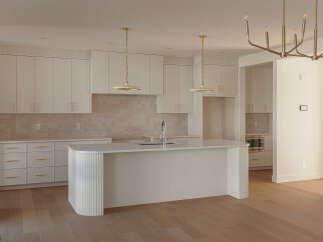 Experience modern luxury in this stunning kitchen featuring sleek white cabinetry with elegant gold hardware.