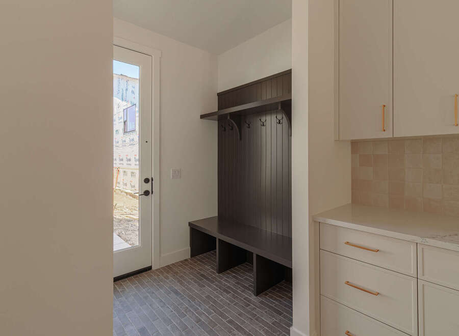 This mudroom features a dark wood built-in bench with a shelf and coat hooks, perfect for organizing entryways.