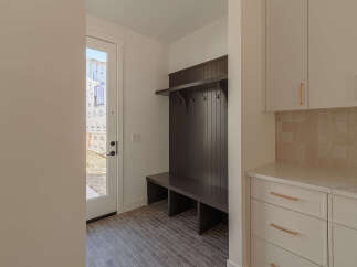 This mudroom features a dark wood built-in bench with a shelf and coat hooks, perfect for organizing entryways.