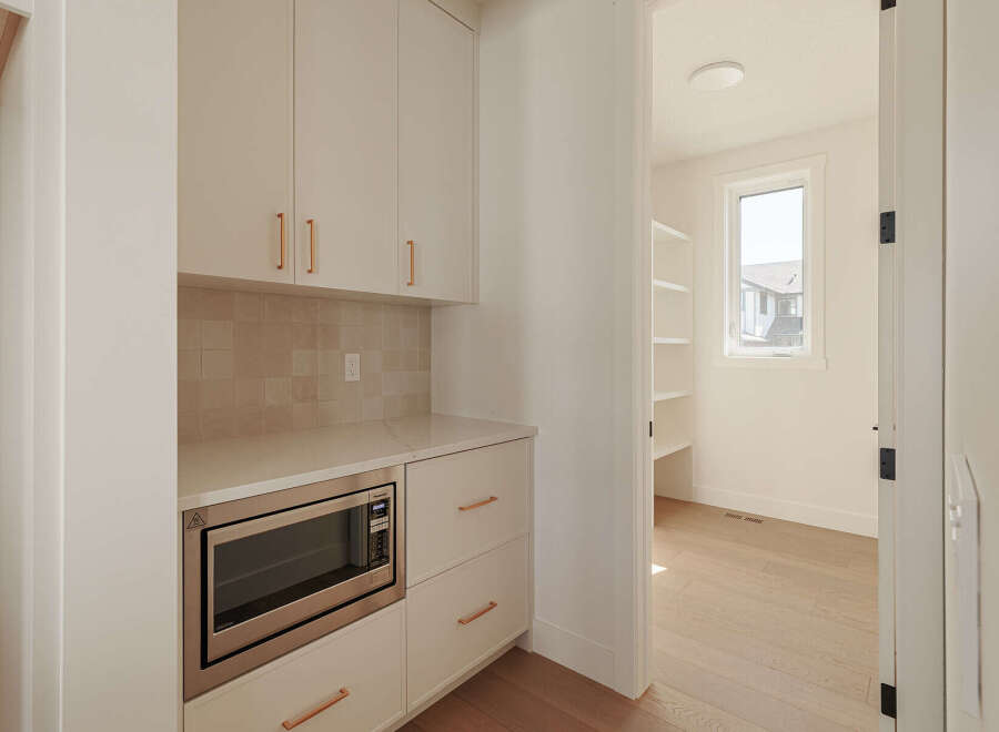 Discover this modern pantry, featuring sleek white cabinetry with elegant rose gold hardware.