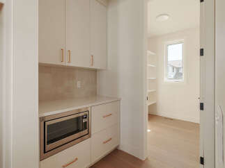 Discover this modern pantry, featuring sleek white cabinetry with elegant rose gold hardware.