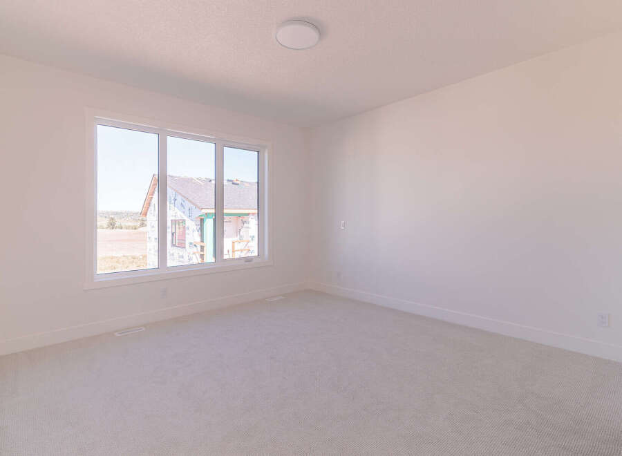 This spacious room features a large window offering ample natural light and a view of the surrounding construction.