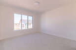 This spacious room features a large window offering ample natural light and a view of the surrounding construction.