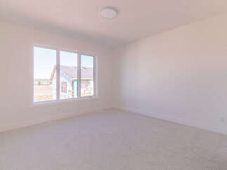 This spacious room features a large window offering ample natural light and a view of the surrounding construction.