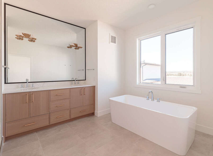 Experience luxury in this modern bathroom, featuring a spacious double vanity with ample storage and a sleek, freestanding soaking tub.