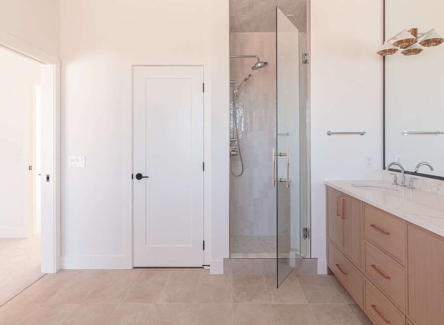Step into this modern bathroom featuring a spacious glass-enclosed shower with a rainfall showerhead and a handheld wand.