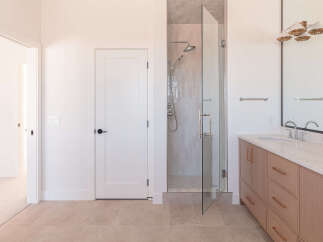 Step into this modern bathroom featuring a spacious glass-enclosed shower with a rainfall showerhead and a handheld wand.
