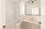 Step into this pristine bathroom, featuring a sleek bathtub with white tiled walls and a modern vanity with a quartz countertop.