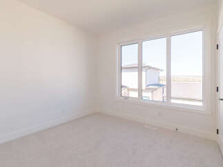 This empty room features a large window that floods the space with natural light, offering a view of neighboring houses and the surrounding landscape.