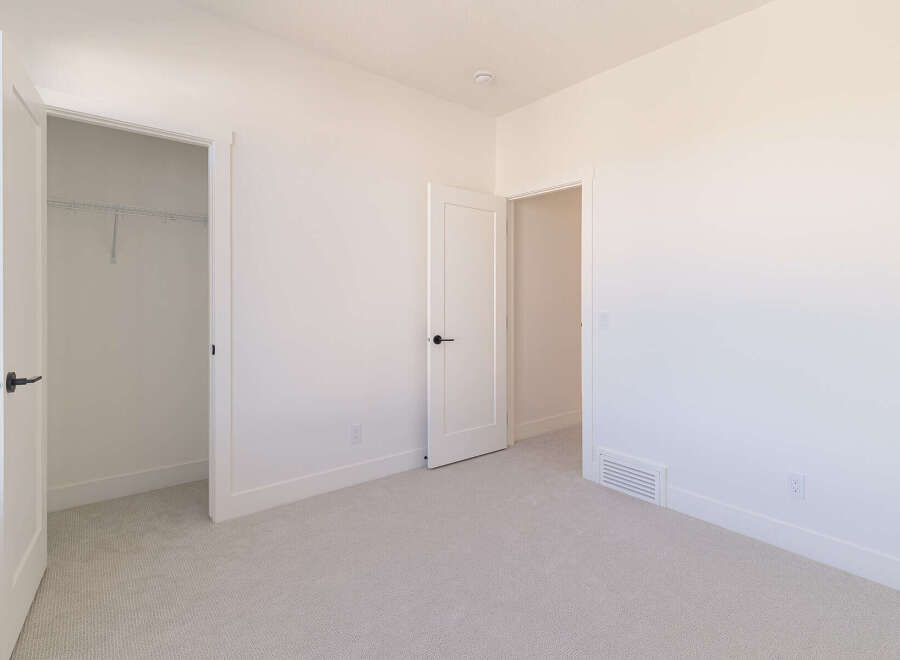 Step into this bright and airy bedroom, featuring a spacious walk-in closet with ample shelving for all your storage needs.