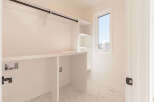 This spacious laundry room features a built-in countertop and shelving, perfect for organizing your laundry essentials.