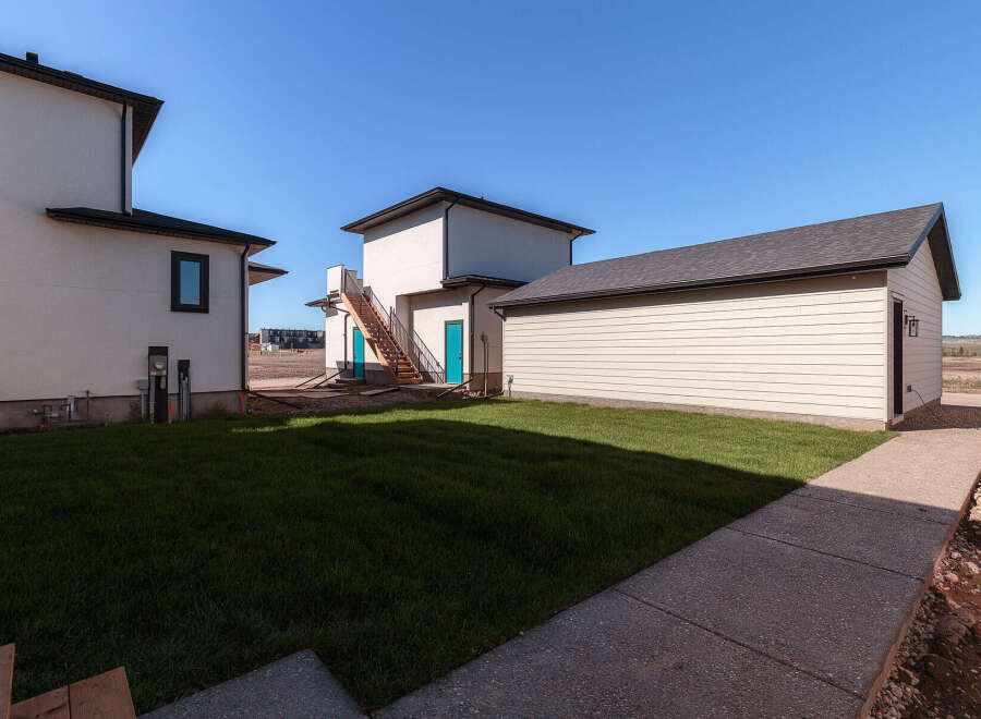 Discover modern living with this newly constructed property, featuring a sleek white exterior and a detached garage.