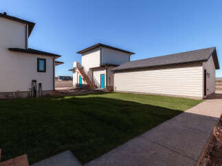 Discover modern living with this newly constructed property, featuring a sleek white exterior and a detached garage.