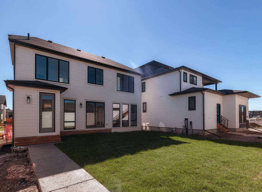 Discover modern living in this stunning new construction home, featuring a sleek white exterior with large black-framed windows that maximize natural light.