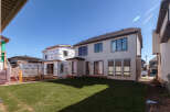 This image showcases a modern home under construction, featuring a sleek white exterior and large, dark-trimmed windows.