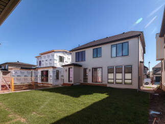 This image showcases a modern home under construction, featuring a sleek white exterior and large, dark-trimmed windows.