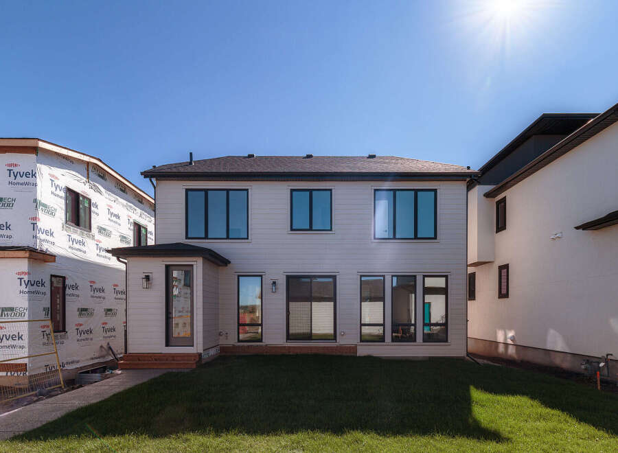 This stunning modern home features a sleek exterior with large, dark-framed windows and light-colored siding.