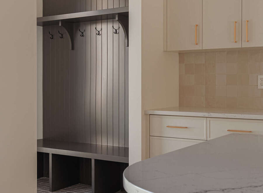 This modern home features a stylish mudroom with a dark wood built-in bench and coat rack, perfect for organization.