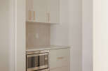 This modern kitchen features sleek, cream-colored cabinetry with elegant brass hardware, offering ample storage.