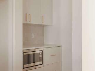 This modern kitchen features sleek, cream-colored cabinetry with elegant brass hardware, offering ample storage.