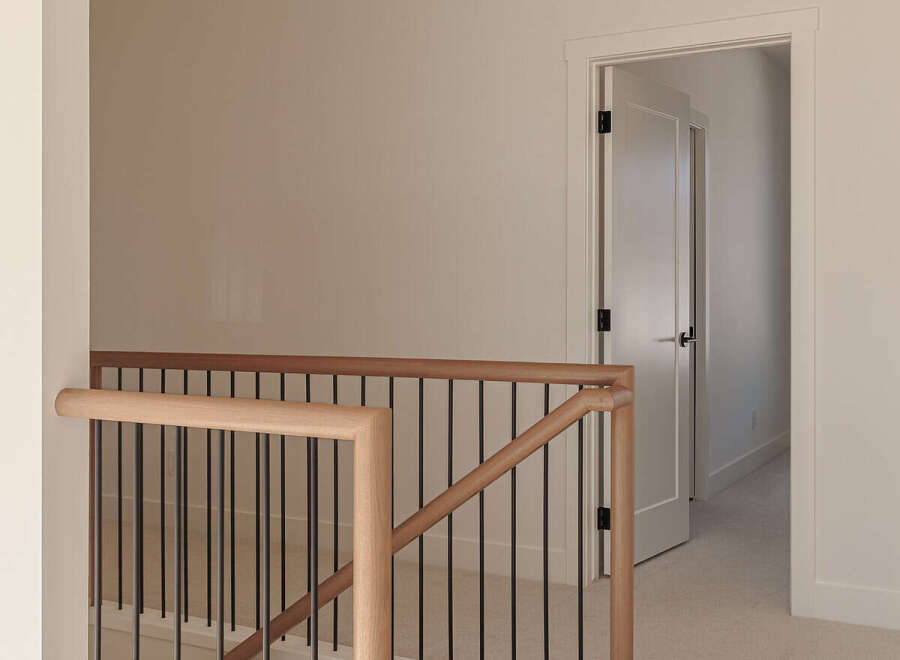 This modern staircase features a sleek design with light wood handrails and black metal spindles, creating an elegant transition between floors.