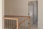 This modern staircase features a sleek design with light wood handrails and black metal spindles, creating an elegant transition between floors.